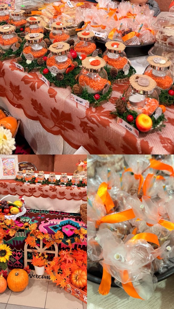 Mese decorată cu borcane cu decoruri de toamnă, conuri de brad și fructe, alături de pungi cu dulciuri ambalate cu panglici oranj.